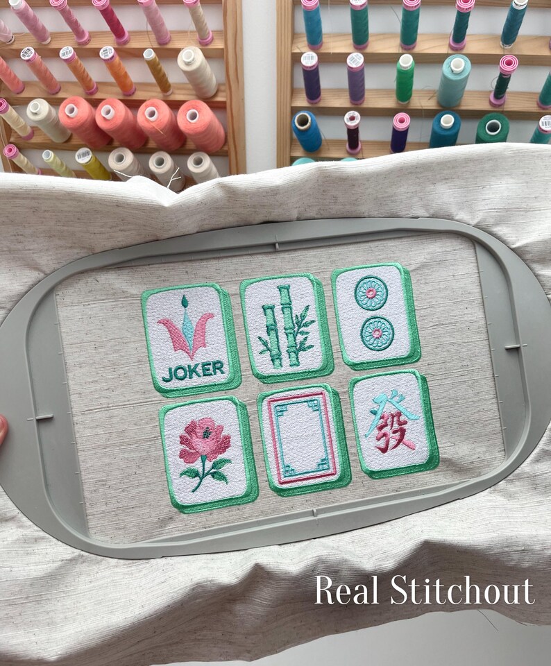 Close up real stitchout of machine embroidered mahjong tile designs showing satin stitch border and thread texture.