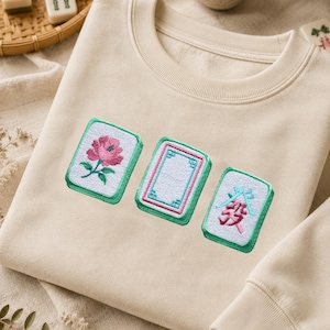 Mahjong embroidery design stitched on a beige sweatshirt.