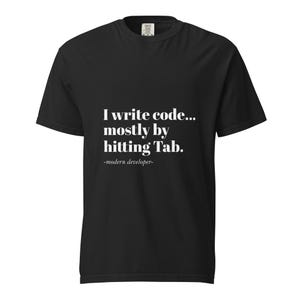 Op de afbeelding: Zwart T-shirt met witte tekst: "I write code... mostly by hitting Tab." Daaronder staat "-modern developer-". Het shirt heeft korte mouwen en een ronde hals.