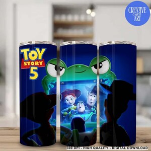 May include: A cylindrical tumbler featuring a dark blue background with the Toy Story 5 logo in yellow and red. The design includes a green alien character and a screen displaying characters from the movie, including a cowboy and a space ranger.