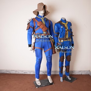 May include: Two mannequins dressed in blue and brown costumes. One mannequin wears a wide-brimmed hat. The costumes have brown straps, pouches, and knee pads. The text "KALSON" is visible on the costumes. The costumes are on display.