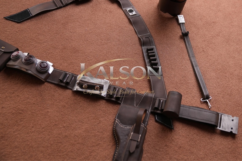 May include: A brown leather utility belt with multiple pouches, holders, and a holster. The belt features white stitching and metal accents. The image also includes a matching shoulder strap and a cylindrical holder. The text "LALSON WEAR" is visible.