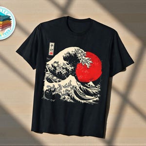 May include: Black t-shirt with a Japanese wave design and a red sun. The graphic is in white, black, and red. The shirt has a crew neck and short sleeves. The design includes Japanese text.
