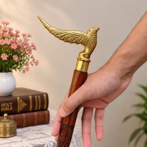 以下が含まれることがあります： 翼を広げた鳥の形をした真鍮製のハンドルが付いた杖。シャフトはダークブラウンの木製で、全体に複雑な花の彫刻が施されており、滑らかな金属製のカラーで真鍮の鳥と接続されています。