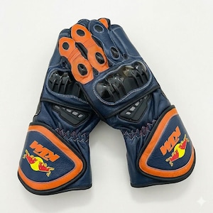 May include: A pair of blue and orange motorcycle gloves. The gloves have black protective panels and the KTM and Red Bull logos. The gloves are made of leather and have orange accents. The gloves are designed for motorcycle riding.