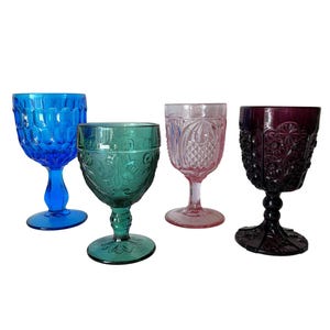 May include: Four vintage goblets in shades of blue, green, pink, and purple. The blue goblet has a honeycomb pattern, the green has a floral design, the pink has a diamond pattern, and the purple has a starburst design.