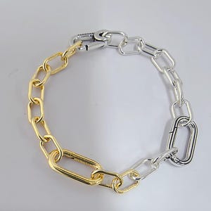 May include: A two-tone bracelet with gold and silver links. The bracelet has a lobster clasp closure, and the brand name "Pandora" is visible on the clasp.