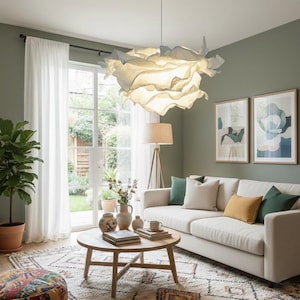 May include: A living room with a large, cream-colored sofa, a round wooden coffee table, and a patterned rug. A large, flower-shaped light fixture hangs from the ceiling. Two framed abstract art pieces hang on the wall.