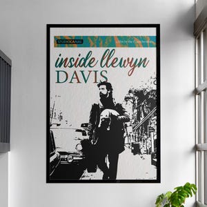 May include: A framed poster featuring the movie title "Inside Llewyn Davis." The poster has a black and white image of a man holding a dog, with the title in teal and red. The StudioCanal logo is at the top.