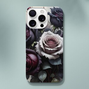 May include: A phone case with a floral pattern of dark purple and white roses. The roses are arranged with green leaves, creating a romantic aesthetic. The case has a glossy finish and a camera cutout.