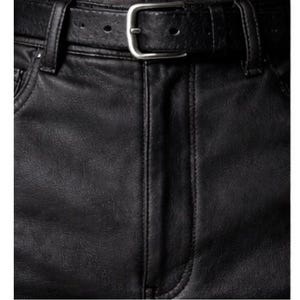 May include: Close-up of black faux leather pants with a matching belt. The belt has a silver-colored buckle. The pants have visible stitching and a classic five-pocket design.