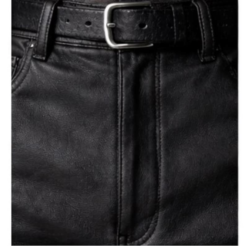 May include: Close-up of black faux leather pants with a matching belt. The belt has a silver-colored buckle. The pants have visible stitching and a classic five-pocket design.