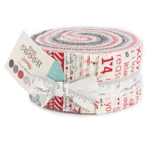 May include: A rolled fabric bundle with red, white, and gray patterns. The bundle is tied with a white ribbon and a measuring tape. A tag reads "First Crush" and "Sweetwater". The fabric is decorated with hearts and the number 14.