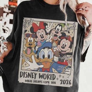 May include: Black t-shirt featuring a vintage-style graphic of Disney characters including Mickey Mouse, Minnie Mouse, Donald Duck, Goofy, and Pluto. The graphic reads "Disney World" and "Where Dreams Come True 2026".