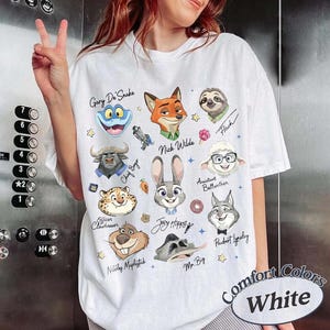 May include: White Comfort Colors t-shirt featuring cartoon character portraits from a movie. The shirt includes the text "Comfort Colors White" and character names like "Nick Wilde" and "Judy Hopps".