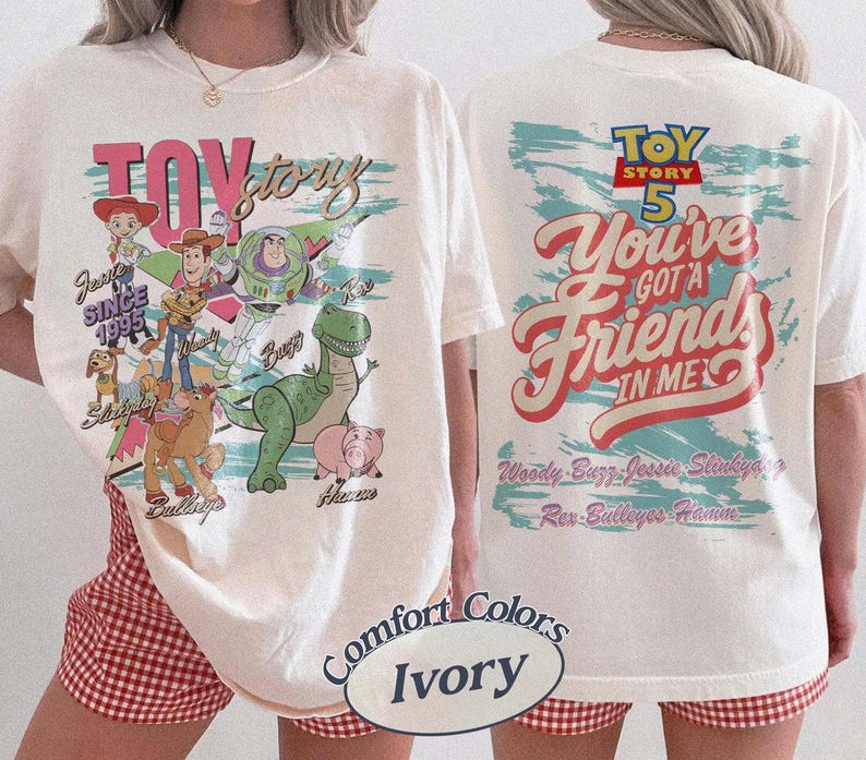 Pode incluir: Uma t-shirt cor de marfim com gr&aacute;ficos das personagens de Toy Story. A frente mostra a Jessie, o Woody, o Buzz Lightyear, o Slinky Dog, o Bullseye, o Rex e o Hamm com o texto Toy Story. As costas apresentam o log&oacute;tipo Toy Story 5 e o texto You've Got A Friend In Me.