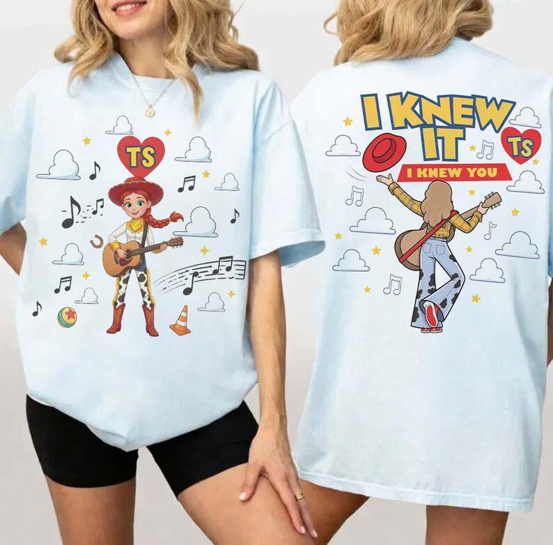 Puede incluir: Una camiseta azul claro con un gr&aacute;fico de una vaquera tocando la guitarra en la parte delantera, y un dise&ntilde;o trasero con el texto I KNEW IT I KNEW YOU, un sombrero rojo, una guitarra y notas musicales rodeadas de nubes y estrellas amarillas.