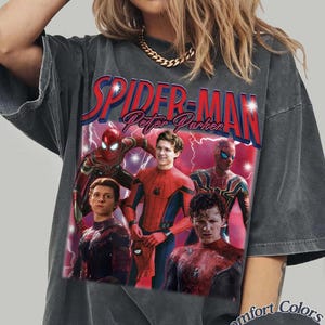 May include: Dark gray t-shirt featuring multiple images of Spider-Man and the text "SPIDER-MAN Peter Parker" in red and blue. The shirt has a vintage look with the words "Comfort Colors Pepper" printed on the bottom right.