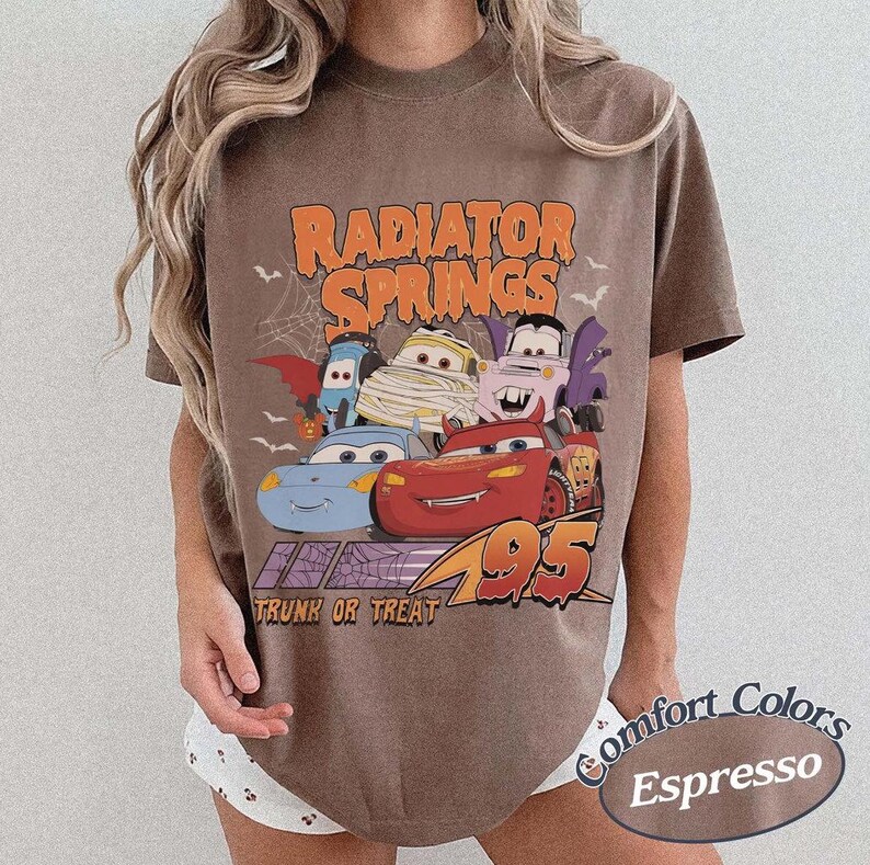 May include: Espresso-colored t-shirt featuring a Halloween-themed graphic of the Cars characters. The design includes the text "Radiator Springs" and "Trunk or Treat 95". The shirt is a Comfort Colors brand.