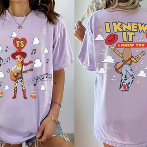 Puede incluir: Una camiseta de color morado claro con un gr&aacute;fico de un personaje vaquero tocando la guitarra en la parte delantera, rodeado de nubes, notas musicales y un coraz&oacute;n con las letras TS. La parte trasera muestra el texto I KNEW IT I KNEW YOU.