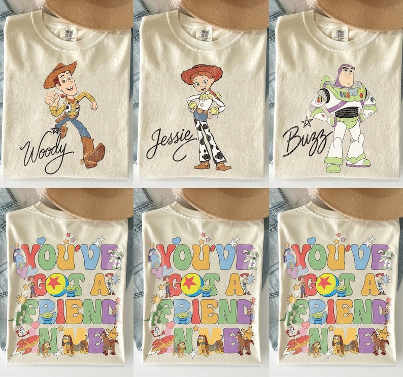 May include: A collection of cream-colored t-shirts featuring Toy Story characters. Three shirts display Woody, Jessie, or Buzz Lightyear with their names in script. Three shirts feature the colorful text You've Got A Friend In Me with characters.