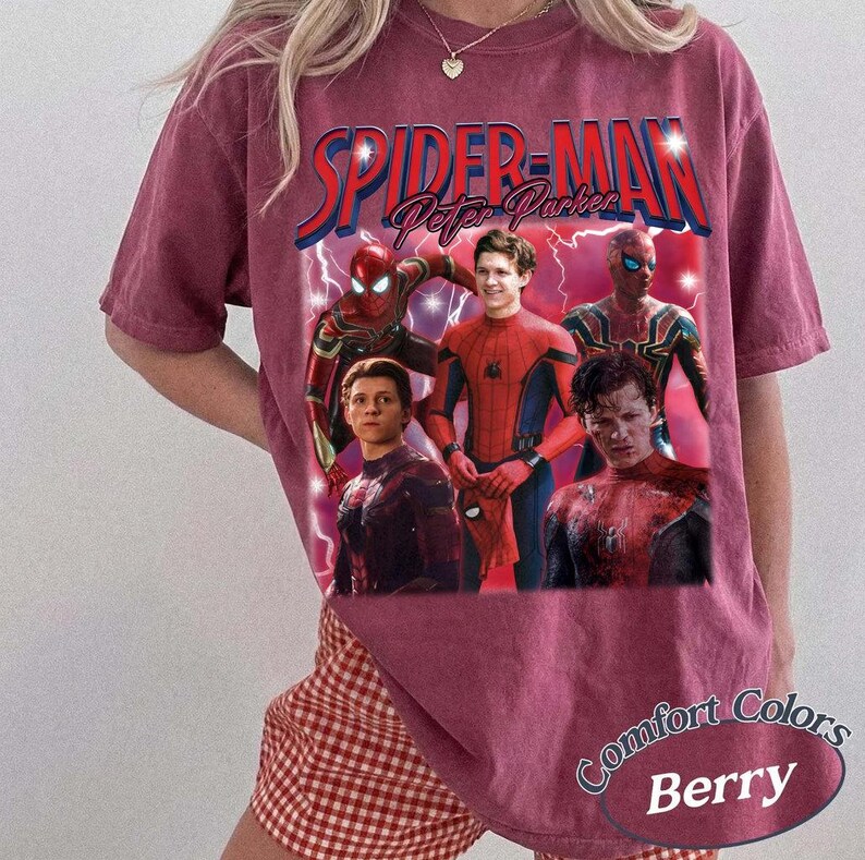 May include: Berry-colored t-shirt featuring a graphic of Spider-Man and Peter Parker. The design includes multiple images of the character, with the words "SPIDER-MAN" and "Peter Parker" in a vintage style. The shirt is labeled "Comfort Colors Berry".