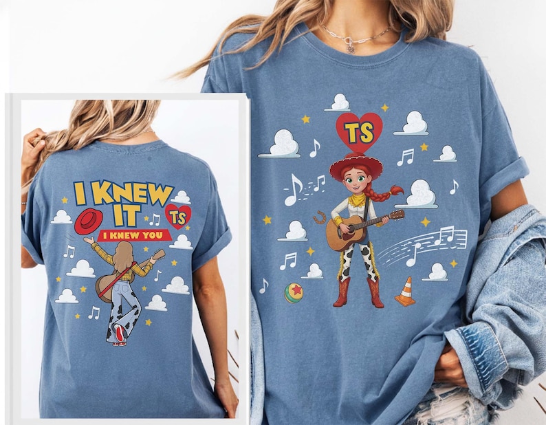Puede incluir: Una camiseta azul con un gr&aacute;fico de una vaquera tocando la guitarra, rodeada de nubes, notas musicales y un coraz&oacute;n rojo con las letras TS. La parte posterior de la camiseta muestra el texto I KNEW IT I KNEW YOU con una ilustraci&oacute;n similar.