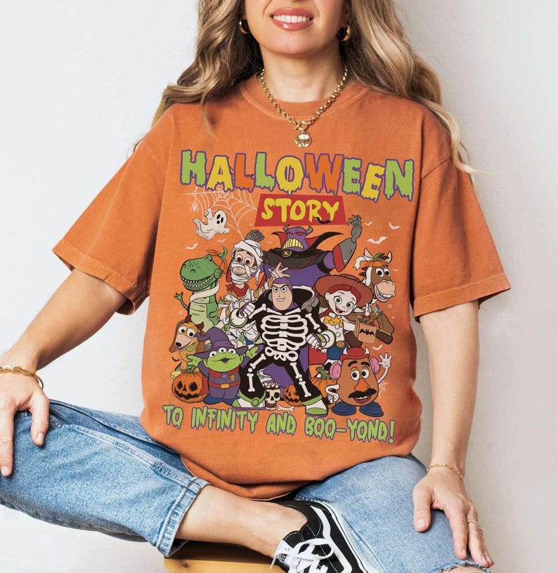 May include: Orange t-shirt with a Halloween-themed cartoon graphic. The text "HALLOWEEN STORY" is at the top, with "TO INFINITY AND BOO-YOND!" at the bottom. The design includes a ghost, dinosaur, and other characters, perfect for Halloween.