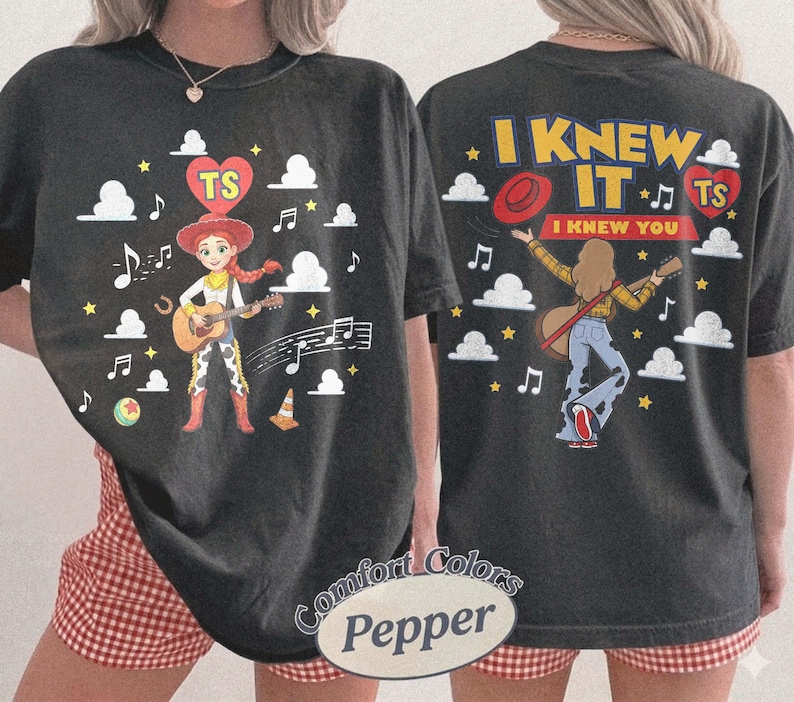 Puede incluir: Una camiseta negra con un gr&aacute;fico frontal de una vaquera tocando la guitarra con notas musicales, nubes y un coraz&oacute;n con las letras TS. El gr&aacute;fico trasero muestra a una persona tocando la guitarra con el texto I KNEW IT I KNEW YOU y un coraz&oacute;n.