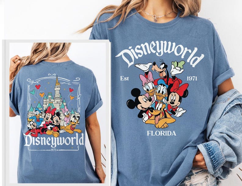 May include: A blue t-shirt featuring Disney characters. The front of the shirt displays the word "Disneyworld" above a group of cartoon characters. The back of the shirt has a castle graphic and the word "Disneyworld".