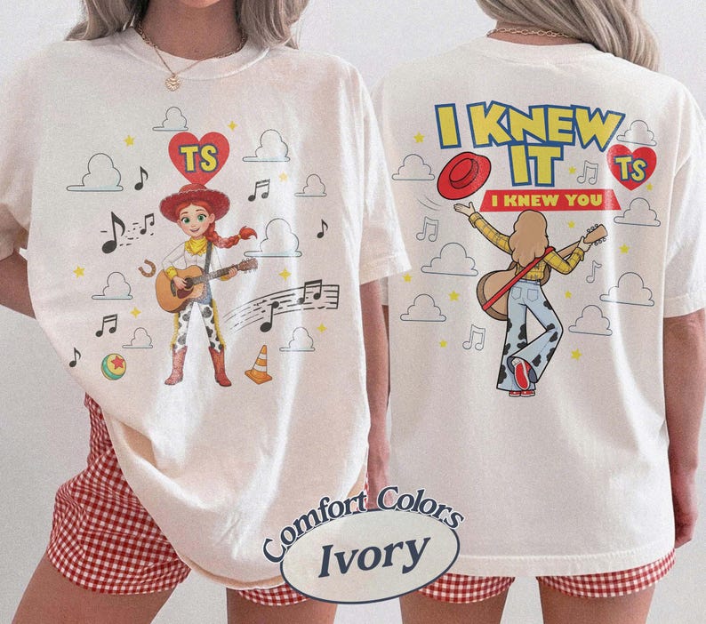 Puede incluir: Una camiseta color marfil con un gr&aacute;fico de una vaquera tocando la guitarra en la parte delantera y trasera. El frente muestra al personaje con notas musicales, nubes y un coraz&oacute;n con 'TS'. La parte posterior muestra el texto 'I KNEW IT I KNEW YOU'.