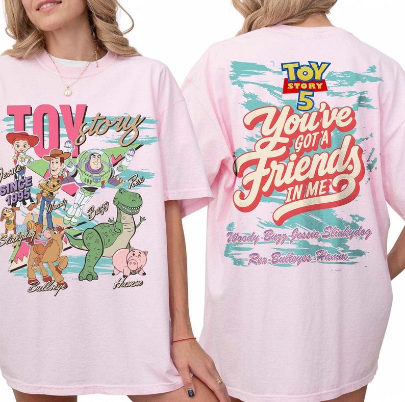 Pode incluir: Uma t-shirt rosa claro com gr&aacute;ficos de Toy Story. A frente mostra Woody, Buzz Lightyear, Jessie, Rex, Slinky Dog, Bullseye e Hamm com o texto Toy Story. As costas apresentam o texto Toy Story 5 You've Got A Friend In Me.