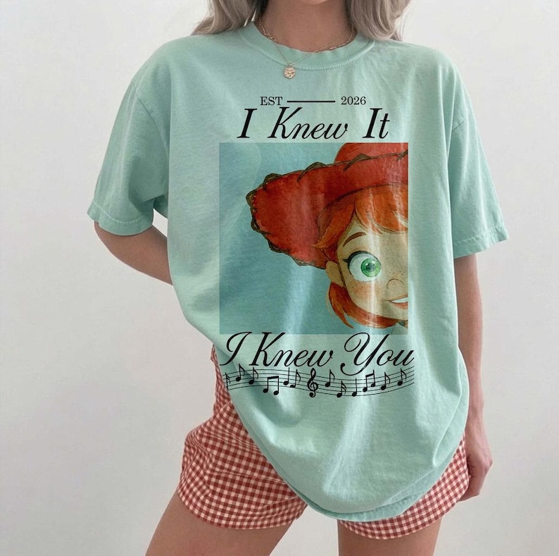 Peut inclure: Un t-shirt &agrave; manches courtes vert clair avec une illustration d'un personnage aux cheveux roux portant un chapeau rouge. Le texte indique EST 2026 I Knew It I Knew You, accompagn&eacute; d'une port&eacute;e musicale noire avec des notes sous l'image.