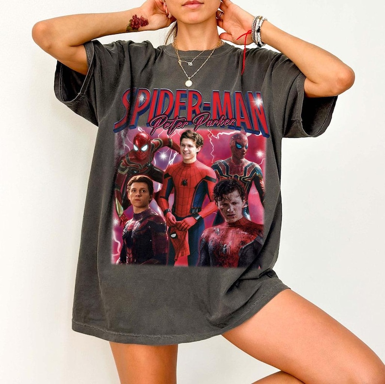 May include: Dark gray t-shirt featuring a graphic of Spider-Man and the text "Spider-Man Peter Parker" in red and white. The graphic includes images of Spider-Man in various poses. The shirt has short sleeves.