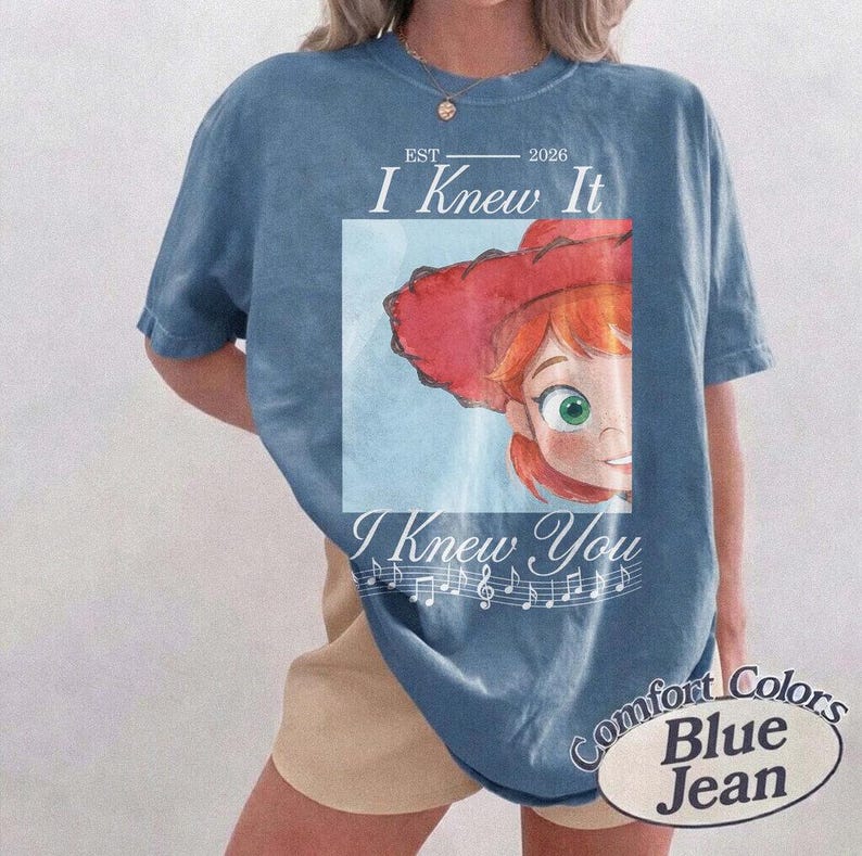 Peut inclure: Un t-shirt bleu &agrave; manches courtes avec un graphique repr&eacute;sentant un personnage aux cheveux roux portant un chapeau de cow-boy rouge. Le texte indique EST 2026 I Knew It I Knew You, avec une port&eacute;e musicale. Le t-shirt a un aspect d&eacute;lav&eacute;.