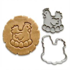May include: A hen-shaped cookie cutter with a matching biscuit and a cut-out. The cookie cutter is grey plastic, and the biscuit is light brown. The hen is sitting on eggs.