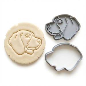 Könnte beinhalten: Ein Set von Hundekeksformen. Das Set enthält einen grauen Kunststoffausstecher, einen passenden Konturausstecher und einen Keks mit dem Gesicht des Hundes. Das Gesicht des Hundes ist im Profil mit langer Schnauze.