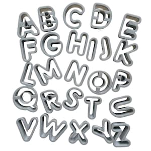 Puede incluir: Un juego completo de veintiséis cortadores de galletas con forma de letras del alfabeto en color gris claro, dispuestos de la A a la Z. Cada letra está formada por un marco grueso y redondeado con un centro abierto y uniforme.