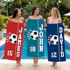 May include: Three personalized soccer towels in red, teal, and blue. Each towel features a soccer ball graphic, the word "Nexus", a name, and a number. The towels are held in front of a swimming pool.