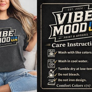 May include: Dark gray t-shirt with the text "VIBE MOOD UA PRINT & APPAREL" in a white and yellow design. The shirt also has care instructions on a black background.