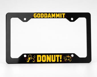 Puede incluir: Un marco de matrícula rectangular negro con texto amarillo que dice GODDAMMIT en la barra superior y DONUT! en la inferior. La sección inferior incluye un gráfico amarillo de una persona cubriéndose la cara y un gato con una corona.