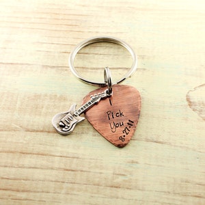 May include: A copper guitar pick keychain with a silver guitar charm. The pick has the words "I Pick You" and the date "8.27.11" engraved on it.