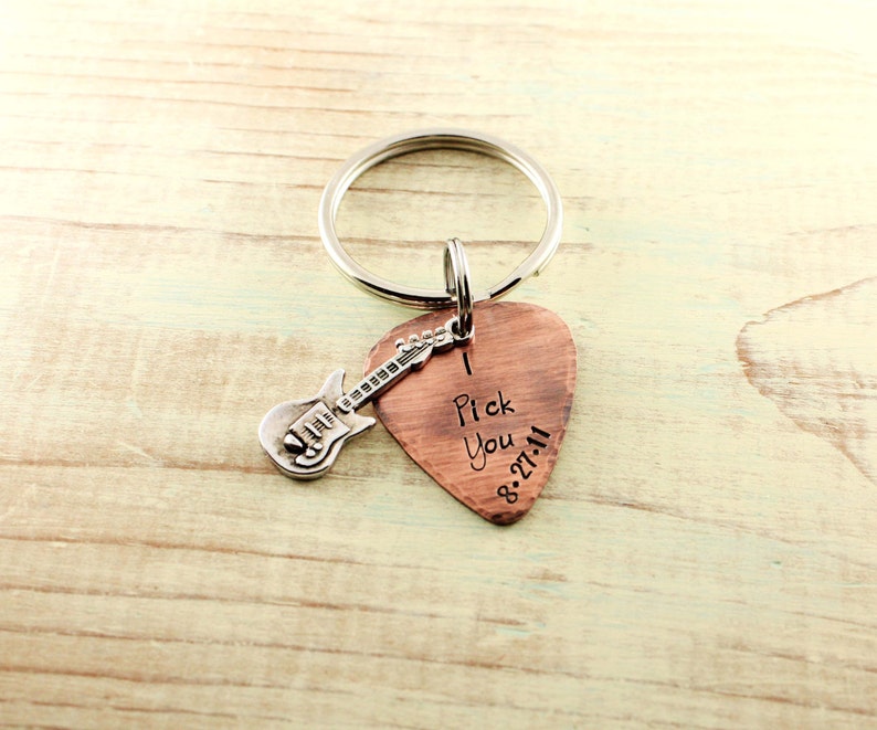 May include: A copper guitar pick keychain with a silver guitar charm. The pick has the words "I Pick You" and the date "8.27.11" engraved on it.