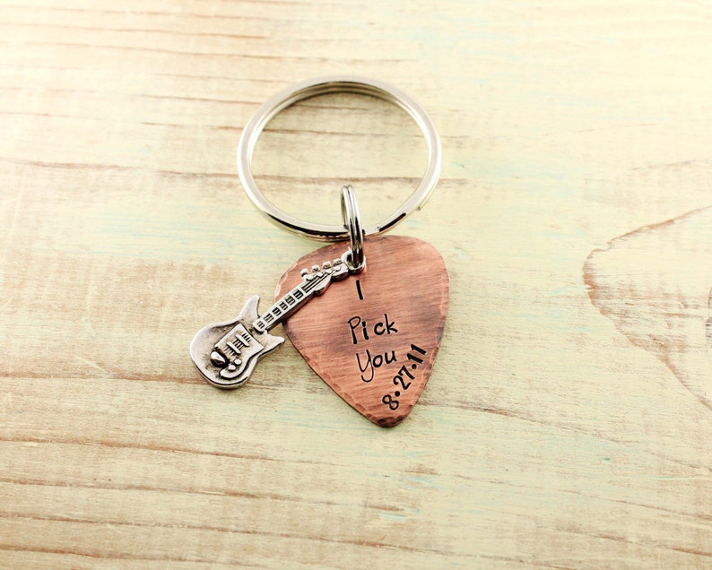 May include: Copper guitar pick keychain with a silver guitar charm. The pick has the words "I Pick You" and the date "8-27-11" engraved on it.