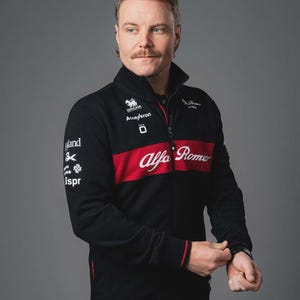 May include: Black zip-up jacket with a red horizontal stripe across the chest. The jacket features the Alfa Romeo logo in white, along with sponsor logos and text. The jacket has a stand-up collar and red trim.