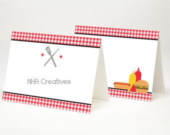 May include: Two red and white checkered table cards with a black border. The left card has a gray spatula and fork crossed over each other with two red stars. The text "NHA Creatives" is below the crossed utensils. The right card has a hot dog, a slice of watermelon, a hamburger, and two bottles of condiments.