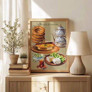 May include: A framed print featuring a Turkish breakfast scene. The image includes a stack of bagels, a casserole, olives, cheese, tea, and a blue and white teapot. The words "Turkish Breakfast" are written at the top of the print.