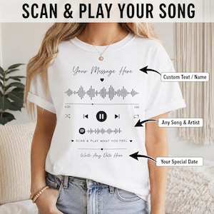 Könnte beinhalten: Ein weißes T-Shirt mit einem schwarzen Grafikdruck einer Musik-Player-Oberfläche. Das Design umfasst eine Schallwelle, Wiedergabesteuerungen, einen Spotify-ähnlichen Code sowie den Text Your Message Here, SCAN & PLAY WHAT YOU FEEL und Write Any Date Here.