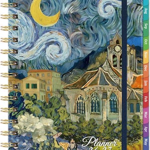 May include: Spiral-bound planner with a cover featuring a painting of a night scene with a church, buildings, and a yellow crescent moon. The planner has a blue elastic band and monthly tabs. The text "Planner 26-27" is visible.