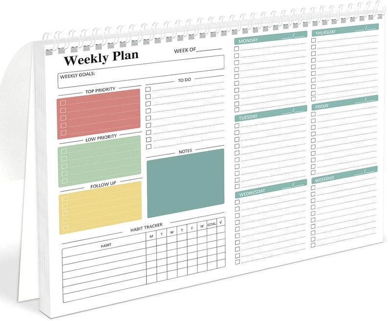 May include: A white spiral-bound weekly planner with a colorful layout. The planner features sections for weekly goals, to-do lists, notes, and a habit tracker. The planner has a red, green, yellow, and teal color scheme.